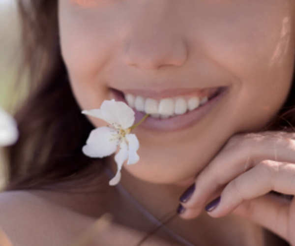 Sourire de femme avec une fleur dans la bouche
